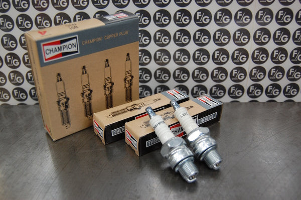 Photo of a pair of Champion L82C spark plugs used in vintage Triumph motorcycles with Franz and Grubb logo in background